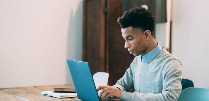 Person sitting at a table working on a laptop