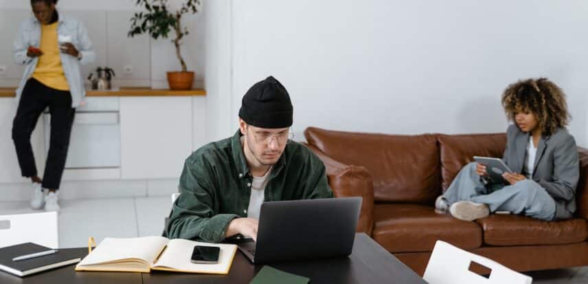 Three people in a room working on phones and laptops